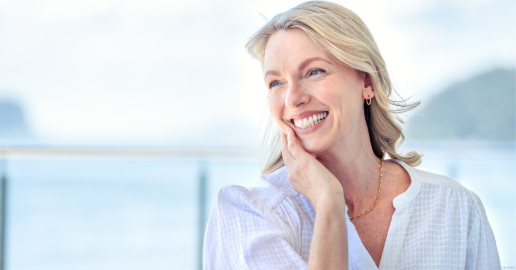 a person smiling with their hand on their chin (model)